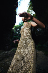 Chivalrous Woman in a woven dress standing in a natural cave setting with a joyful atmosphere.