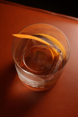 Clear Cocktail with Orange Peel Garnish on Orange Leather