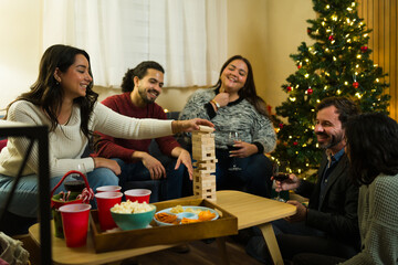 Joyful celebration with friends playing a block stacking game during christmas