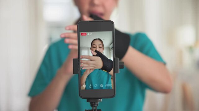 Young adult woman asia people anti aging expert modern nurse live talk video call selfie camera mobile phone app mental health care Online digital virtual asian vlogger filming hand wrist pain physio.