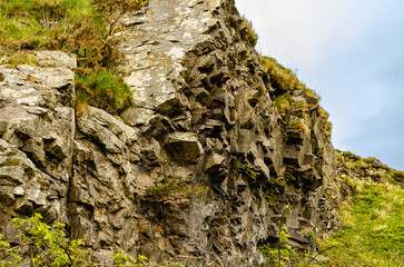 Close-up of a rugged weathered rock formation covered with patches of moss, showcasing natural erosion textures and geological detail under soft daylight at the Isle of Mull.