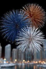 Vivid blue, gold and silver fireworks exploding over modern city skyline at night. Perfect festive background for New Year, Christmas and celebration designs
