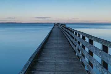 Obraz premium ニュージーランド オークランドの郊外にあるコーンウォリス・ビーチの夕暮れ時の桟橋の上からの風景