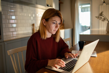 Middle aged woman working on laptop at home