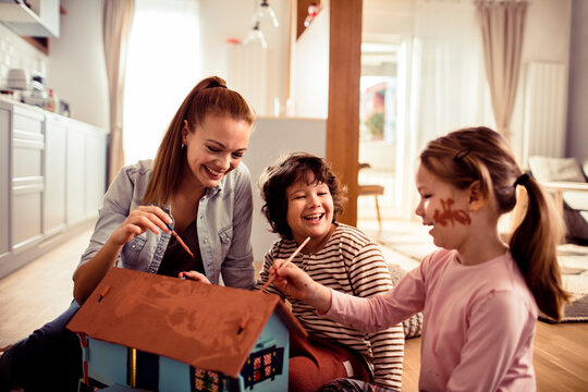 Mother painting a toy house with her children
