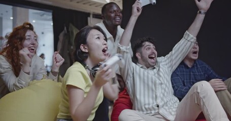 Diverse colleagues enjoy a break from work, playing video games and having fun together in the office. - Powered by Adobe