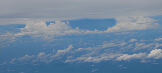 Fototapeta premium Aerial view of scattered cumulus clouds over a deep blue expanse, indicating flight altitude.
