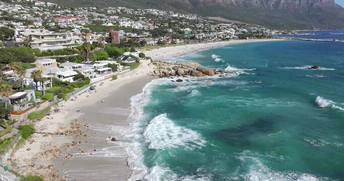 Aerial tilt up shot of Camps Bay beach on a sunny day in Cape Town, Western Cape, South Africa.
