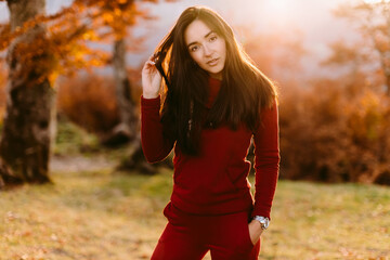 beautiful woman relax in autumn forest. Portrait of long hair woman in warm outfit walk in forest at sunset. 