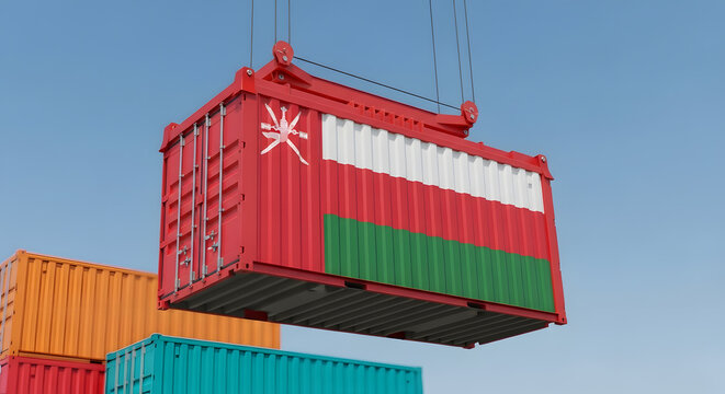 A large shipping container featuring the flag of Oman is being lifted by a crane against a clear blue sky.