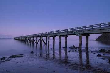 Fototapeta premium ニュージーランド オークランドの郊外にあるコーンウォリス・ビーチの桟橋の風景と黄昏時の空