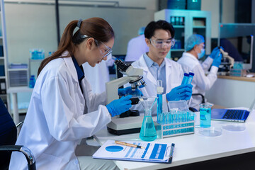 Team of biochemical research scientists working with a microscope for vaccine development