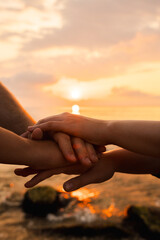 Hands joined together at sunrise over the sea