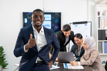 portrait of black businessman in formal suit standing thumb up, group of multiracial team colleague diverse employee coworker meeting performance planning in finance office