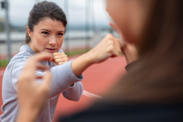 Woman training boxing punches in outdoor gym with focus