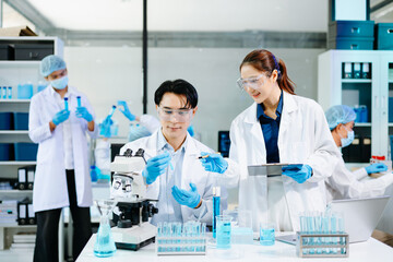 Scientists collaborating in a modern lab with microscopes and blue liquids, representing biotechnology, chemistry, and medical research innovation.