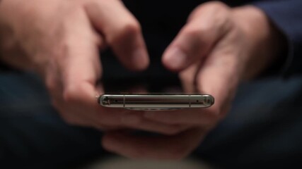 close up view male hands holding and using mobile phone, scrolling and tapping on screen while browsing internet or checking social media notifications at home. - Powered by Adobe