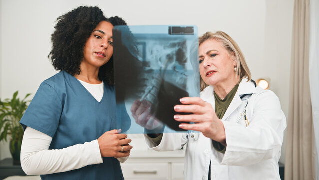 Two Medical Professionals Review X-Ray Image Together During Clinic Consultation and Collaboration - Powered by Adobe