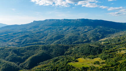 Fototapeta premium Drone photo showing vast green mountain terrain, forested slopes and open fields in natural daylight