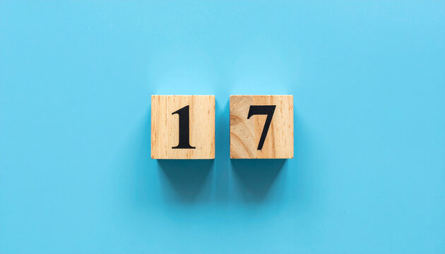 Wooden cubes with number 17 on smooth blue background, top view.