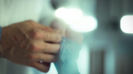 A health professional is putting on blue gloves in a clinical setting to ensure cleanliness and safety before attending to patients. This moment showcases attention to hygiene and preparedness