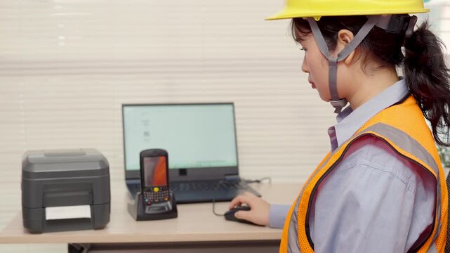 Asian female engineer uses a laptop or notebook to print barcode stickers on a barcode printer.