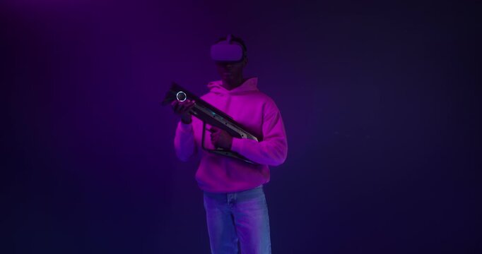 A man in a virtual reality headset with a blaster in his hands in a VR studio