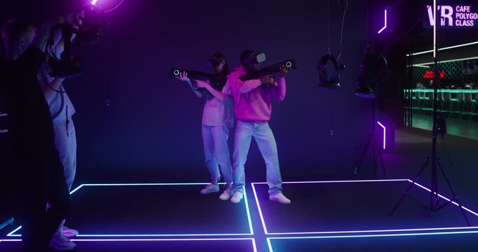 A man and a woman in virtual reality headsets play an online game using game guns