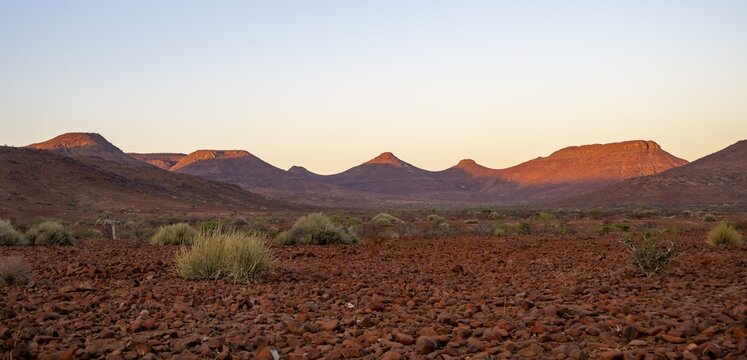 Red glowing table mountains at sunrise, barren dry desert landscape near Palmwag, Damaraland, Kunene, Namibia