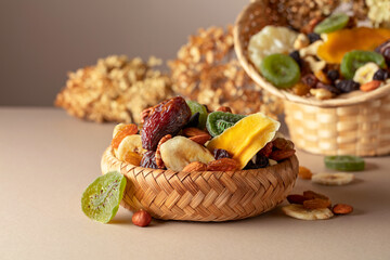 Dried tropical fruits, nuts and raisins on a beige background.