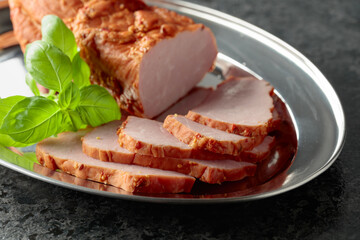 Delicious smoked ham with basil on a metal tray.