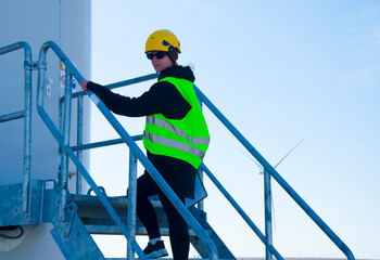 Naklejka premium Engineer working in front of wind turbines for checking wind turbines of the field. Alternative energy concept.