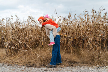 Mother and daughter walking playing together in corn field.