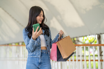 Woman holding smartphone browsing summer sale searching for deals at fashion store, shopping lifestyle at modern mall, online shopping, e-commerce, discount season, customer enjoy digital technology