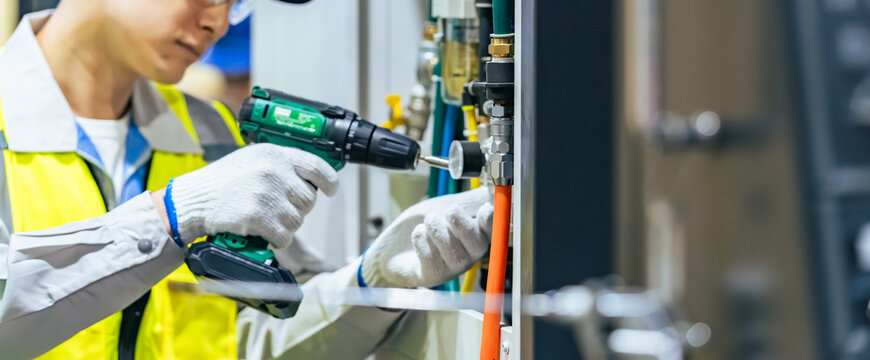 A worker performing maintenance on a machine tool at a factory