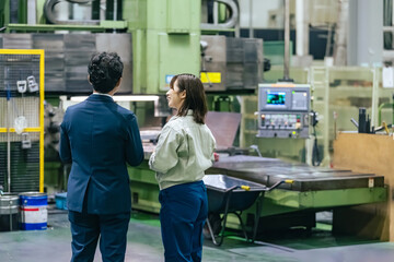 A male businessman and a female worker inspecting a factory