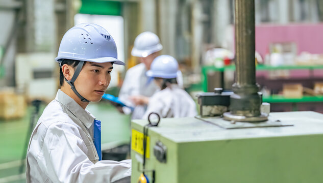 工場で操作盤で機械を操作する男性作業員