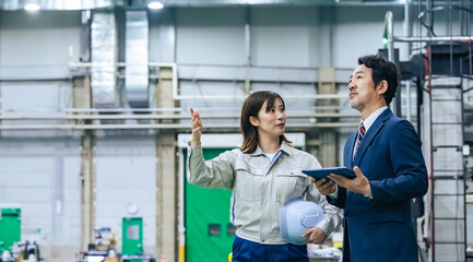 A male businessman and a female worker inspecting a factory