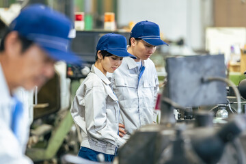 工場で工作機械を操作する作業員グループ