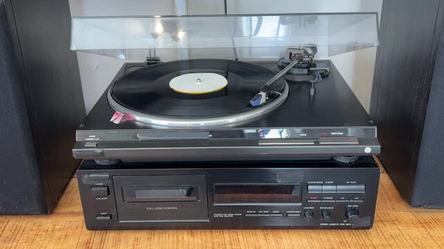Plano general del equipo de sonido con el tocadiscos funcionando y el disco de vinilo girando, 4K