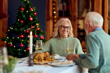 Happy Seniors Share Christmas Dinner With Partner By The Christmas Tree For A Cozy Holiday Evening