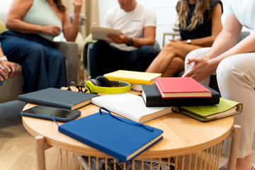 Diverse books and devices on coffee table during group discussion