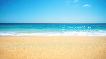 Obraz premium A serene beach scene featuring soft golden sand and a clear blue ocean under a bright sky, creating a tranquil and inviting atmosphere.