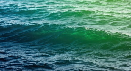 Obraz premium Deep blue and green ocean waves ripple with sunlight.