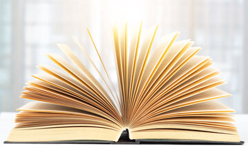 Open book side view on white tabletop and blurred background.