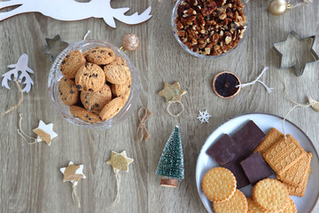 Various Christmas decorations, cookies, chocolate and nuts on wooden background. Flat lay.