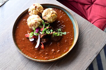 Traditional Czech venison goulash with bread dumplings, autumn seasonal dish served in a restaurant, rustic comfort food.