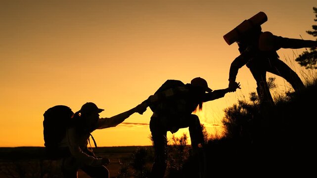Teamwork group people tourists climbing mountain nature. Travelers man woman holding hands climbing mountain, silhouette. Travel, teamwork climbing summit. Teamwork business people. Team businessmen - Powered by Adobe