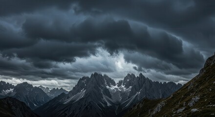Obraz premium Dramatic storm clouds gather over jagged mountain peaks.