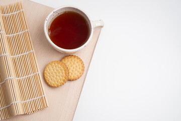 Cozy morning scene with a cup of coffee, tea, and two cookies on a wooden table. Warm natural light creates a calm and relaxing atmosphere, perfect for lifestyle, breakfast, or cozy home concepts.